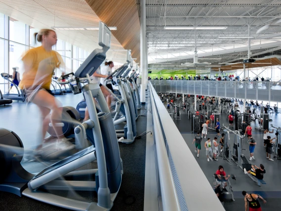 Blurred photo of student on exercise bike, with other students working out in the background