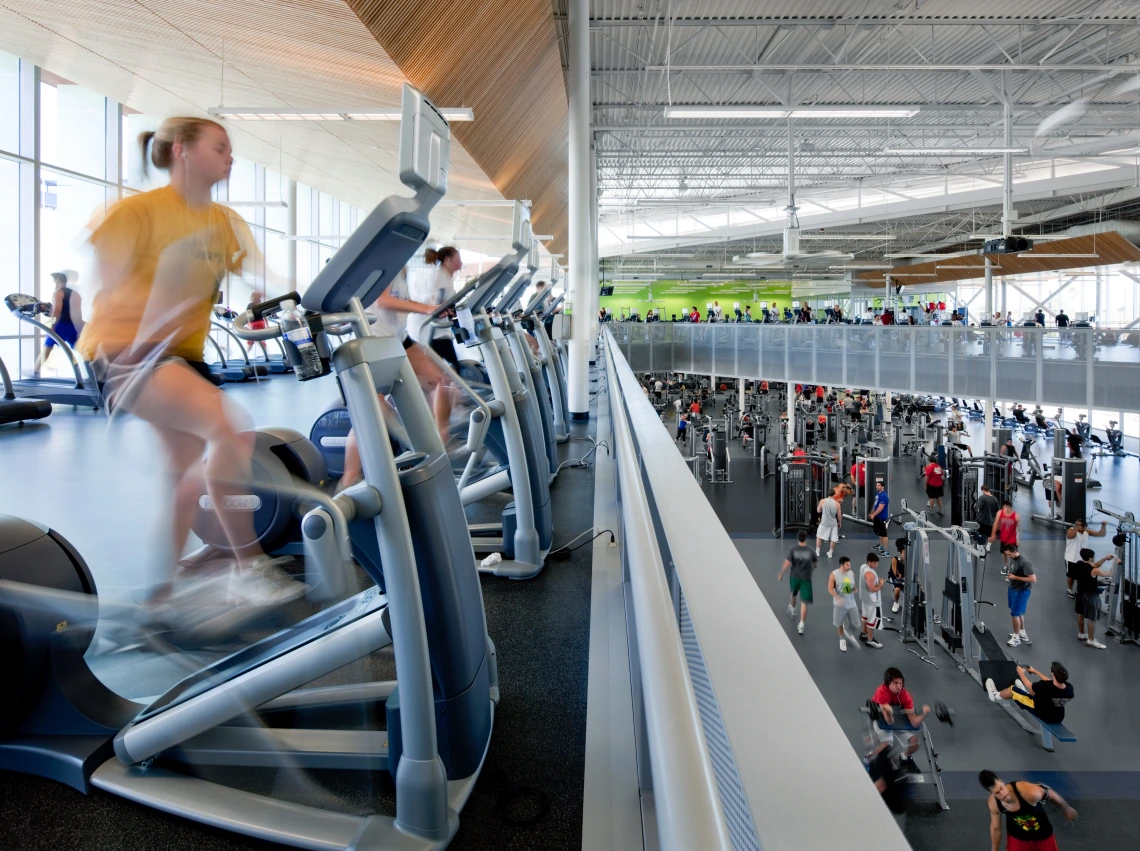 Blurred photo of student on exercise bike, with other students working out in the background